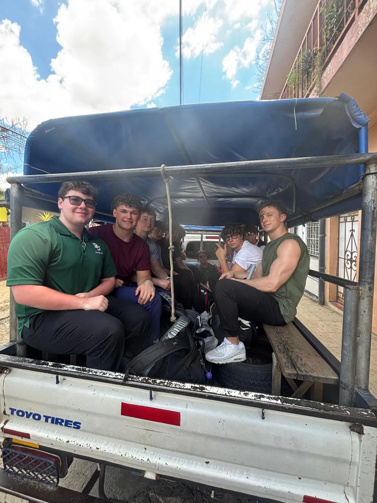 Levi and a group riding in the bed of a covered pickup truck.