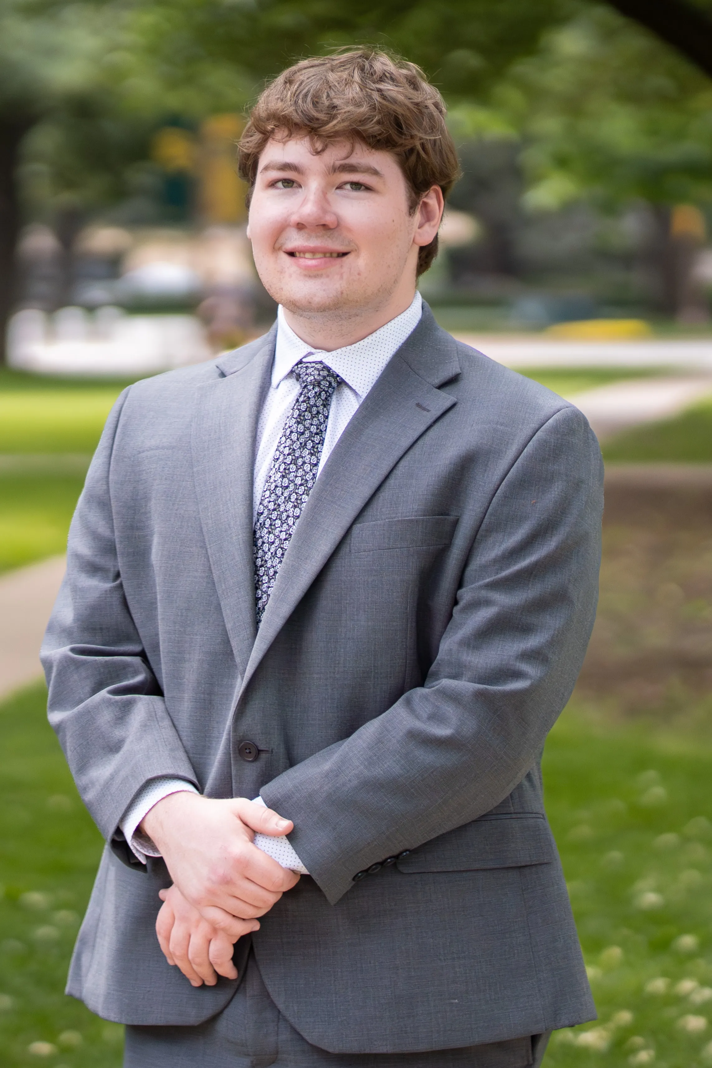 Levi Lobbes, in a grey suit on Baylor's tree-lined campus