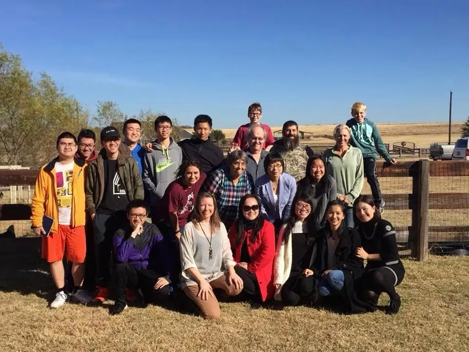 A large group of family and hosted exchange students posed outdoors on a ranch.